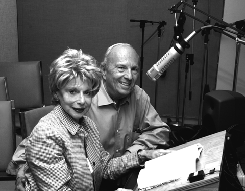 Image: The Gitlins, a pair of JBI volunteers, sitting in the recording booth preparing to read a book