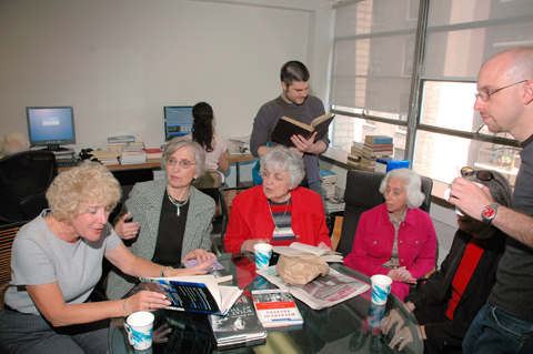 Image: A group of JBI volunteers chatting while reviewing books in the recording studio